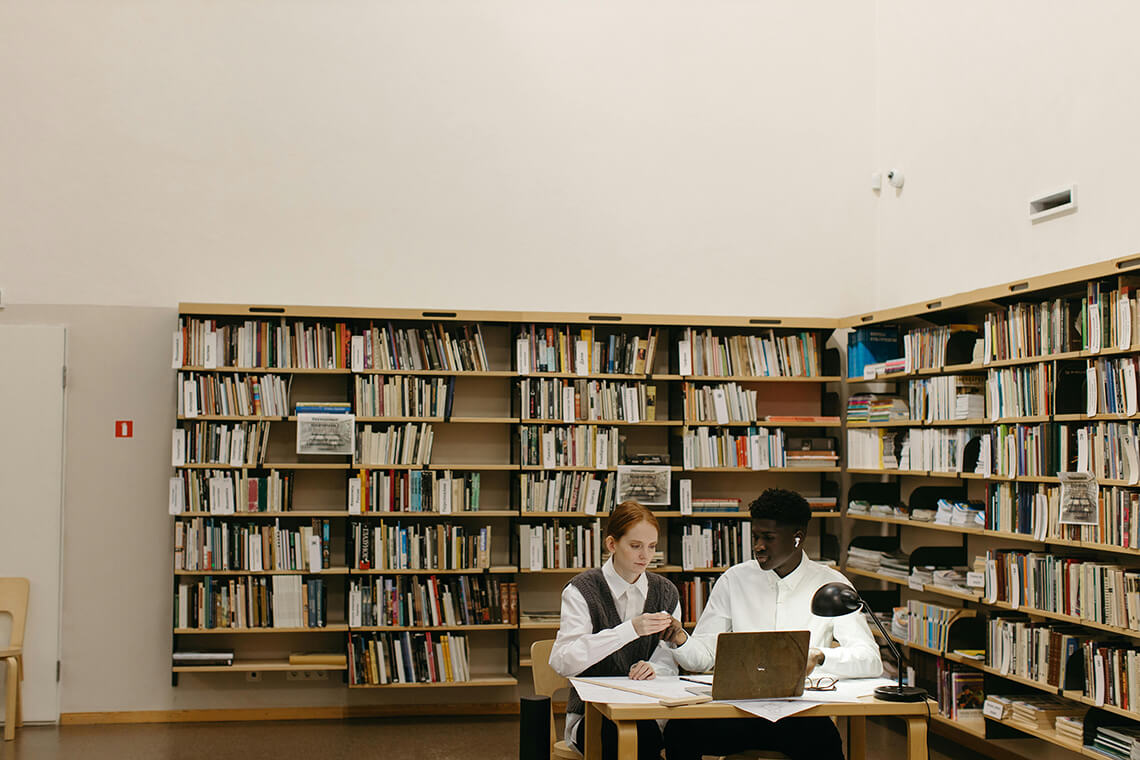 Dos personas estudiando en una biblioteca con luz natural — imagen que representa el aprendizaje compartido sobre refugios climáticos y urbanismo sostenible