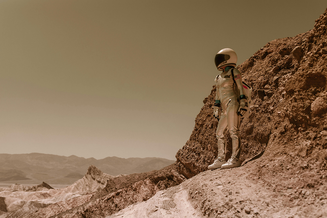 Persona con traje espacial caminando por un paisaje árido, metáfora visual del calor extremo urbano sin refugios climáticos