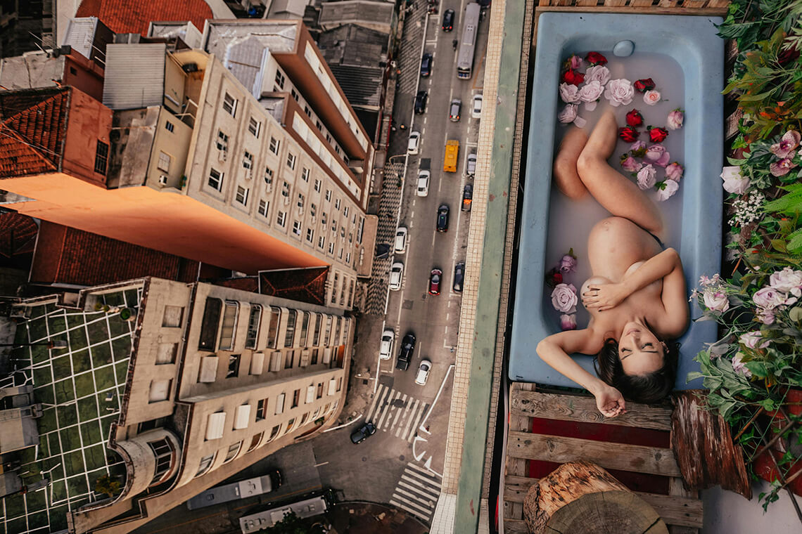 Mujer embarazada descansando en una bañera con flores en un balcón urbano — imagen simbólica de refugio climático íntimo en la ciudad